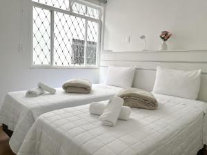 two white beds in a room with a window at Apartamento em Belo Horizonte in Belo Horizonte