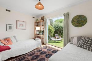 Una sala de estar con dos camas y una ventana. en Beach Bach, en Point Lonsdale