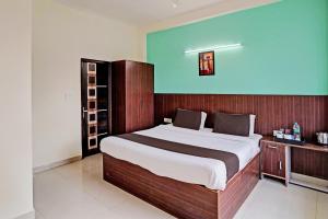- une chambre avec un grand lit et une tête de lit en bois dans l'établissement Super OYO Golden Imperial Near PVR Ansal Plaza Greater Noida, à Greater Noida