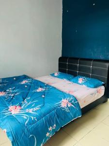 a bed with a blue comforter with flowers on it at Abang payung sierra perdana in Masai