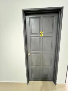 Una puerta negra con un número amarillo. en EMPIRE HOMESTAY PAKA ROOM 3, en Paka