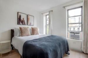 a white bedroom with a large bed and two windows at Lovely 3 Bedroom Apartment in New York