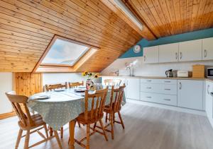 a kitchen and dining room with a table and chairs at Tyn Coed in Moelfre