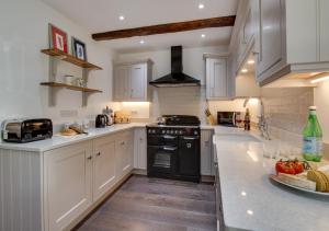 a kitchen with white cabinets and a black stove at Memories Cottage in Milnthorpe