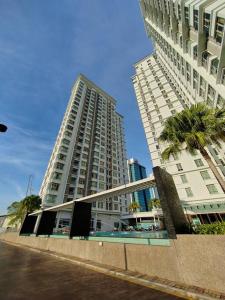 un grand bâtiment blanc avec des palmiers devant lui dans l'établissement Shaftsbury 1 BR w Netflix Wi-Fi, à Cyberjaya