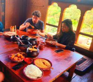 a man and a woman sitting at a table with food at Nobgang B&B (Restaurant and Lodge) in Punākha
