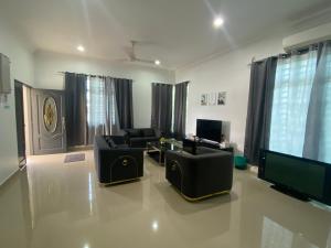 sala de estar con muebles negros y TV de pantalla plana en EMPIRE HOMESTAY PAKA ROOM 3A, en Paka