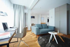 a living room with a blue couch and a desk at ipartment Frankfurt Europaviertel in Frankfurt