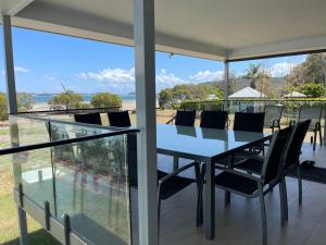 a dining table and chairs on the balcony of a house at ABSOLUTE BEACHFRONT Port Stephens - Pindimar Beach House in Pindimar