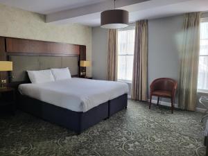 モンマスにあるThe King's Head Hotel - JD Wetherspoonの大きなベッドと椅子が備わるホテルルームです。