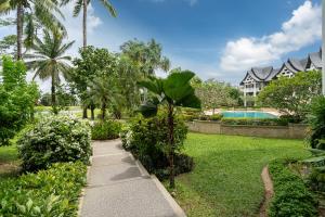 a garden with a sidewalk and a swimming pool at Spacious 2BR Apartment Allamanda II in Laguna, 10 min from BangTao Beach in Bang Tao Beach