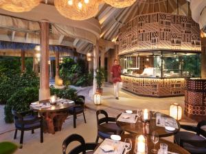 a person walking through a restaurant with tables and chairs at The Nautilus Maldives in Baa Atoll
