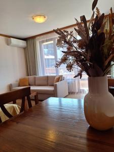 un jarrón con flores en una mesa de madera en la sala de estar en Cozy studio with balcony in 4-star hotel Saint Ivan Rilski, Bansko en Bansko