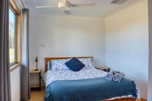 1 dormitorio con 1 cama con edredón azul y ventilador de techo en Kangarooby Cottage - A Peaceful Off-grid Escape, 