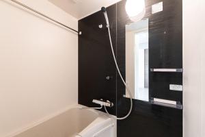 een badkamer met een douche, een wastafel en een spiegel bij JASPER Waseda in Tokyo