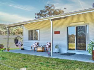 una casa amarilla con dos mesas en un patio en Kangarooby Cottage - A Peaceful Off-grid Escape, 