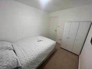 Dormitorio blanco con cama y armario en South Cottage en Hardingstone