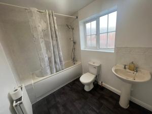 a white bathroom with a toilet and a sink at South Cottage in Hardingstone