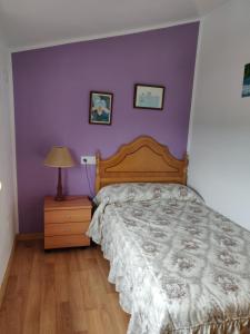 1 dormitorio con cama y pared púrpura en O Faiado, en Crucero