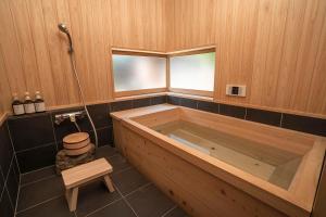 a large wooden tub in a bathroom with a stool at NIPPONIA平福宿場町 in Sayo