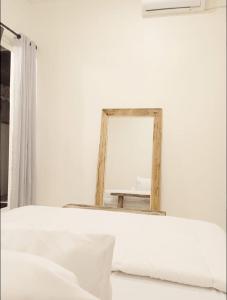 um espelho numa parede branca ao lado de uma cama em Classic Local House Grenceng em Denpasar