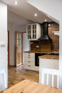 a kitchen with white cabinets and a brick wall at Apartament Piękny Widok in Bardo