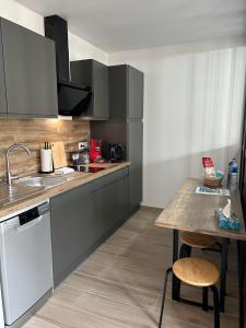 cocina con armarios grises, mesa y fregadero en Studio centre-ville, proche des thermes, en Thonon-les-Bains