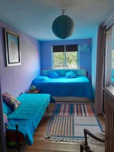 1 dormitorio azul con 2 camas y ventana en Là Haut-Lé Beau, en Le Lambert