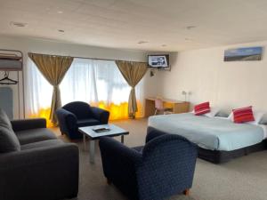 a hotel room with a bed and chairs at Dukes Midway Lodge in Auckland