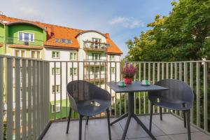 eine Terrasse mit 2 Stühlen und einem Tisch auf einem Zaun in der Unterkunft GREEN PORT Apartament Lwowska with SWIMMING POOL Kołobrzeg by Renters in Kołobrzeg