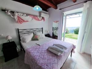 a bedroom with a bed with a purple blanket and a window at Forestata Village in Lixouri