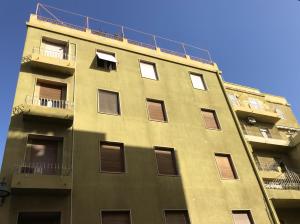 un edificio giallo alto con finestre e balcone di La Tigre Appartamento Con Terrazza In Centro a Cagliari