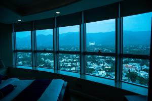 een slaapkamer met ramen met uitzicht op de stad bij Centaurus Hotel Suites in Islamabad