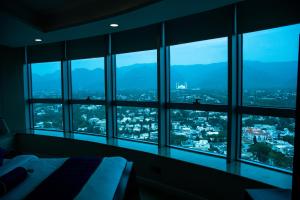 a bedroom with views of a city from windows at Centaurus Hotel Suites in Islamabad