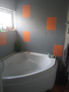 a bath tub in a bathroom with orange and gray tiles at chambre dans maison coquette et accueillante in Dunkerque