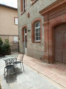 un patio con 2 sillas y una mesa frente a un edificio en LA MAISON DU SOLEIL, en LʼIsle-Jourdain