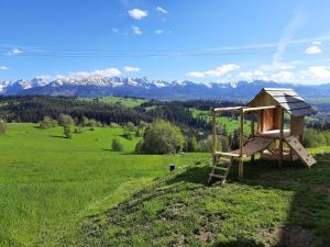 a wooden playground in a field with mountains in the background at Bajka w Gliczarowie in Bukowina Tatrzańska