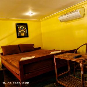 een bed in een kamer met een gele muur bij The Mango Tree Guesthouse in Kampot