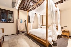 una camera da letto con letto a baldacchino con tende bianche di Yangzhou Aihehua Boutique Homestay a Yangzhou