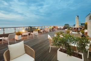 eine Terrasse mit Stühlen und Tischen auf einem Gebäude in der Unterkunft Marine Hotel by Zdrojowa in Kołobrzeg