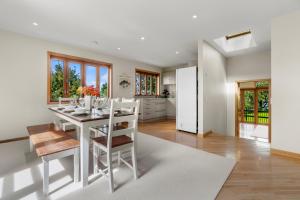 a kitchen and dining room with a white table and chairs at Beachside Luxury - Laingholm Holiday Apartment in Titirangi