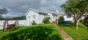 a white house with a yard with a chair at Grey-door cottage Number1 in Glendinningvale