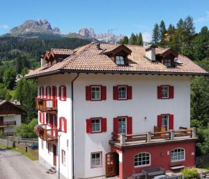 a white and red house with red shutters at Dolomites Hotel La Meridiana in Moena