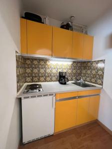 a small kitchen with yellow cabinets and a sink at Apartment „Bergblick“ in Sankt Johann in Tirol
