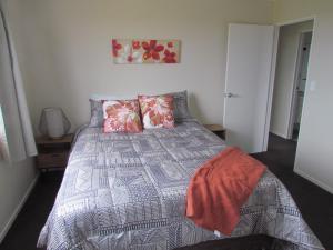 een slaapkamer met een bed met een dekbed en kussens bij West Coast Wonder 4 Minutes Drive to Glinks Gully in Te Kopuru