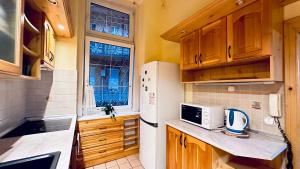 una pequeña cocina con armarios de madera y nevera blanca. en Ulloi Apartment - Unique Style near Corvin, en Budapest