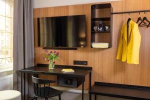 een kamer met een tafel met een tv en een vaas met bloemen bij Hotel La Diligence in Obernai