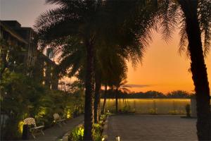 a sunset from the patio of a resort with palm trees at Anagata Hotels and Resorts Tanjung Benoa in Nusa Dua