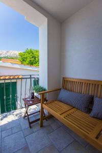 a wooden bench sitting on a balcony with a table at Apartments Baška in Baška