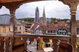 a table on a balcony with a view of a city at Hotel La Diligence in Obernai